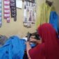 Tampak aktivitas ibu rumah tangga tengah menjahit baju pesanan dari pelanggan.