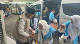 Wakil Wlikota Sungai Penuh, Azhar Hamzah saat membantu salah seorang jemaah haji berjalan menuju asrama haji