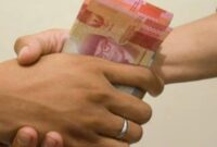 hand is giving bribe. money handshake.  man shaking hands after agreeing deal with indonesian rupiah on brown background