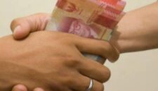hand is giving bribe. money handshake. man shaking hands after agreeing deal with indonesian rupiah on brown background